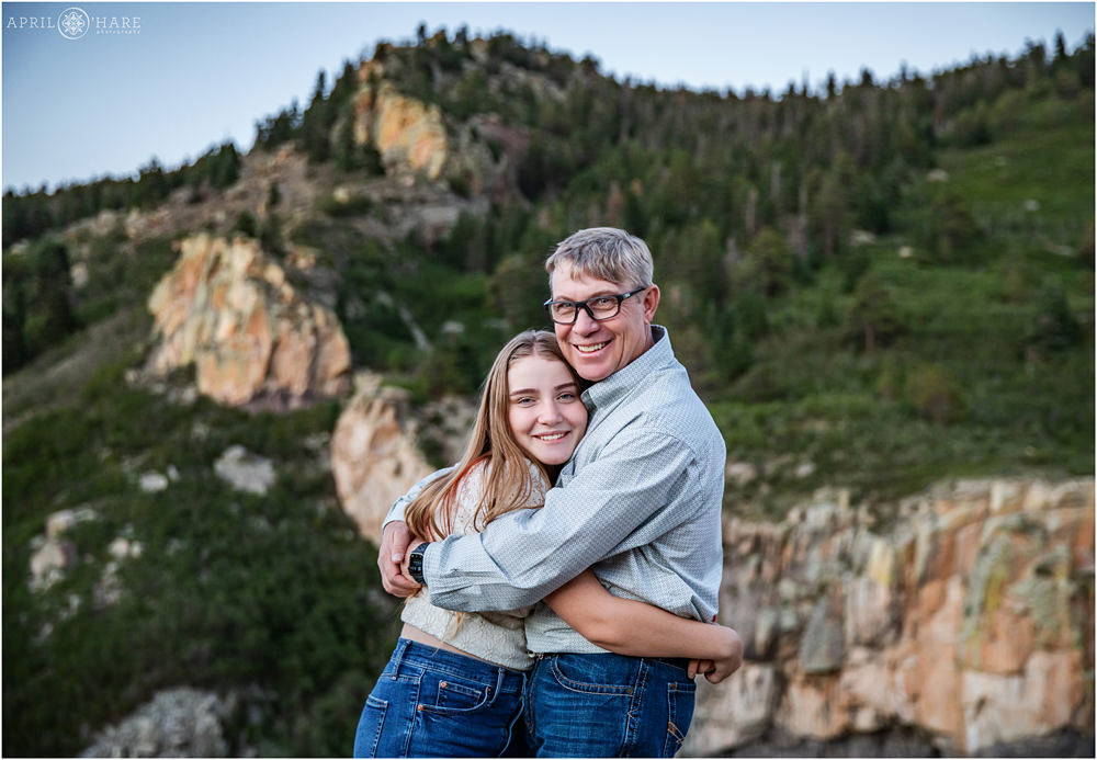 A teenage girl hugs her dad in front of a beautiful rocky backdrop at Lovers Leap in Southern Colorado