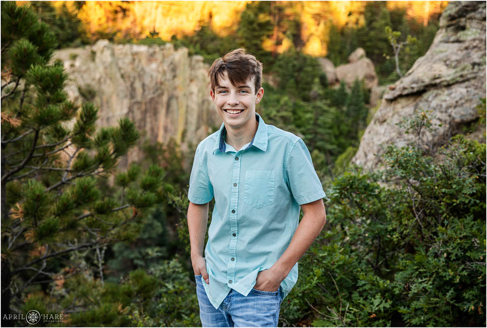 Young teenage boy wearing a short sleeve button up teal blue shirt poses in front of a beautiful backdrop at Lovers Leap in Colorado