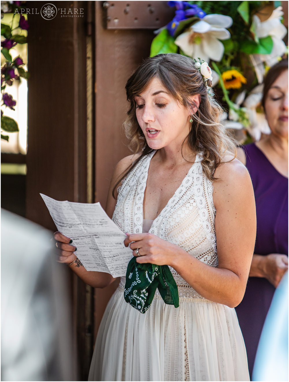 Bride reads her vows at her outdoor wedding in front of a small cute barn on Lookout Mountain in Colorado