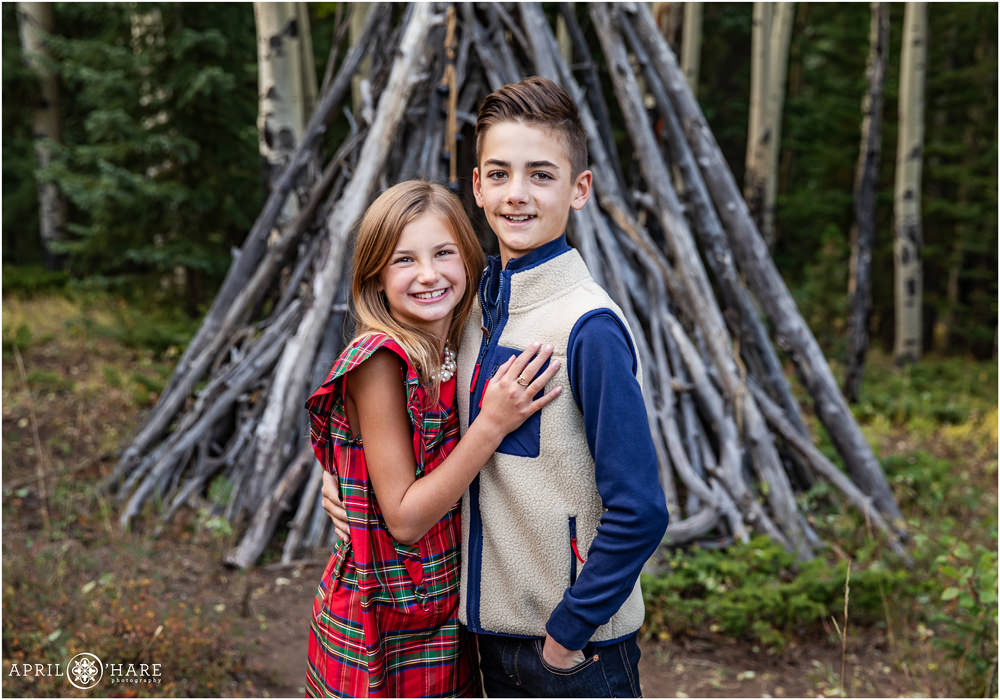 Cute Sibling Photo in front of Wood Tipi in a Colorado Forest