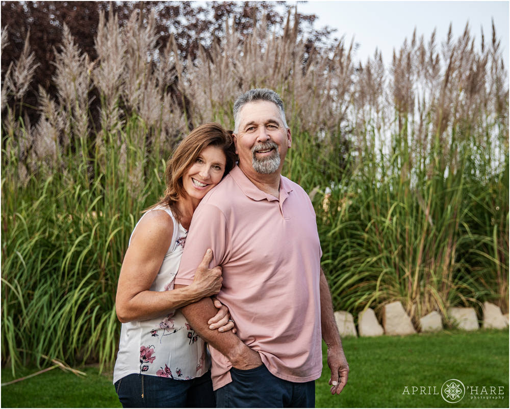 Couple poses together in front of pretty tall pampas grasses at their Erie Colorado home