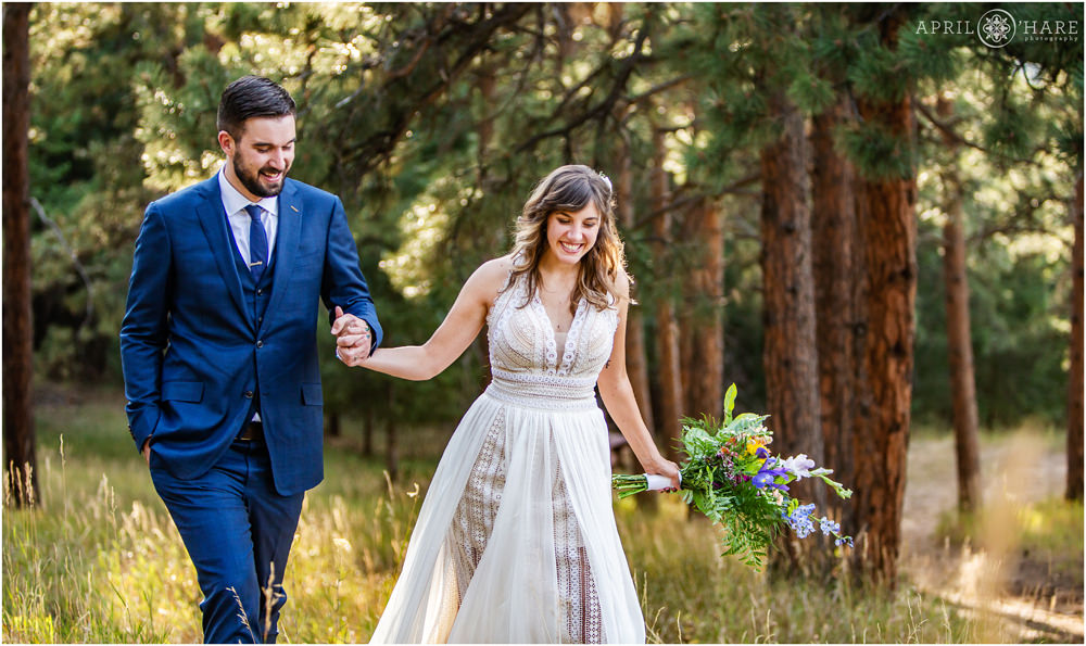 Bride and groom smile as a they walk through the woods in a Colorado forest