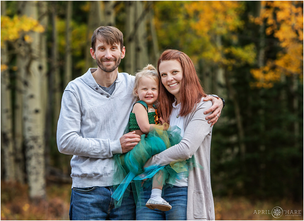 A sweet family photo for a family of 3 with golden aspen tree backdrop during fall