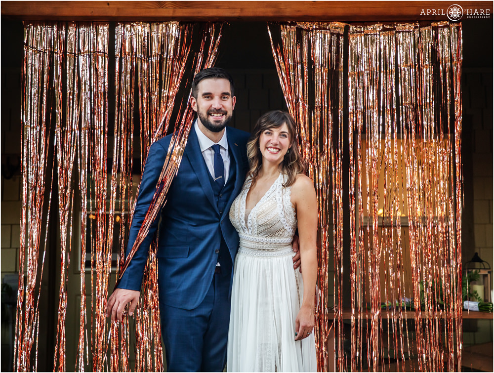 Bride and groom pose with their rose gold curtain streamer at their small intimate Colorado wedding