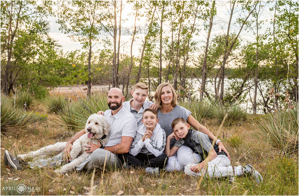 Sweet photo of a family of five cuddling on the ground together at their Aurora Reservoir family portrait session in Colorado