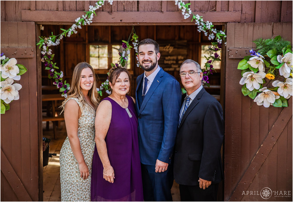 Groom poses for a family picture with his side of the family at his rustic Colorado wedding