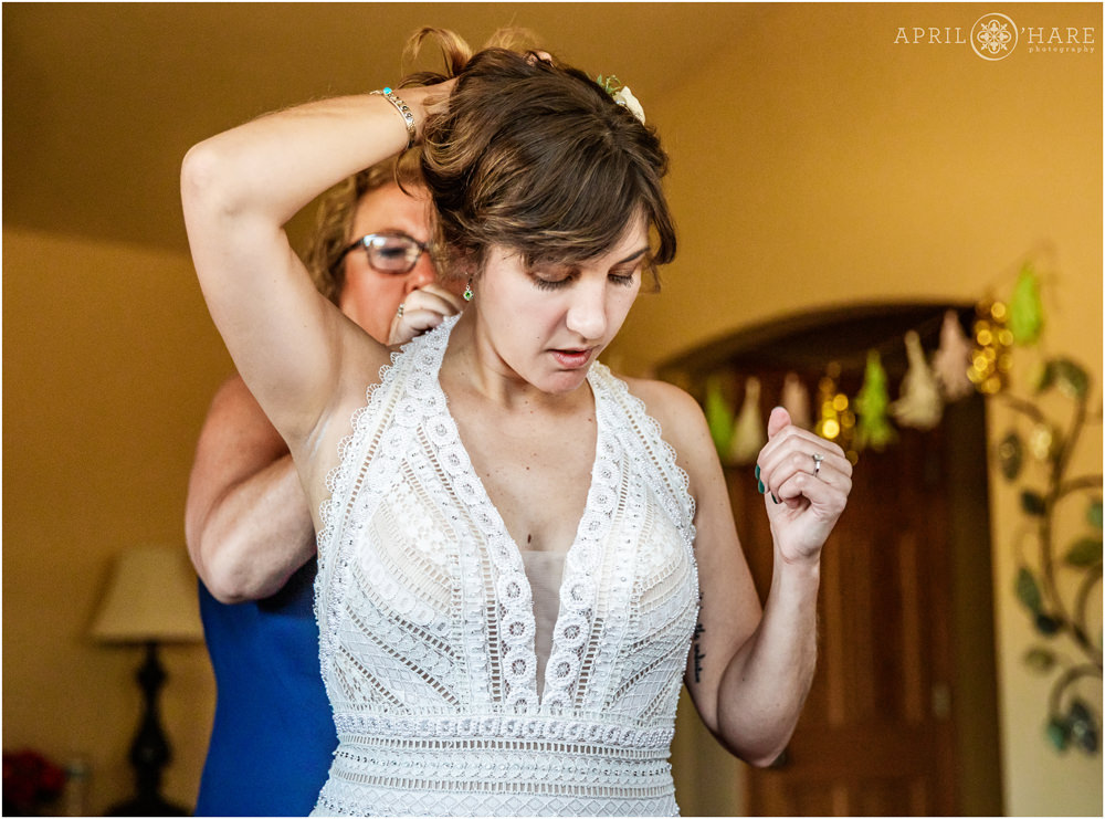 Bride gets help with her bridal gown from her mom on her wedding day in Colorado