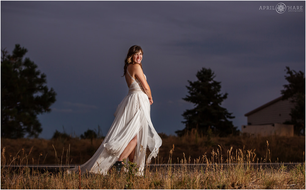 Bride twirls with her pretty wedding gown in front of a pretty purple sunset sky on Lookout Mountain in Colorado
