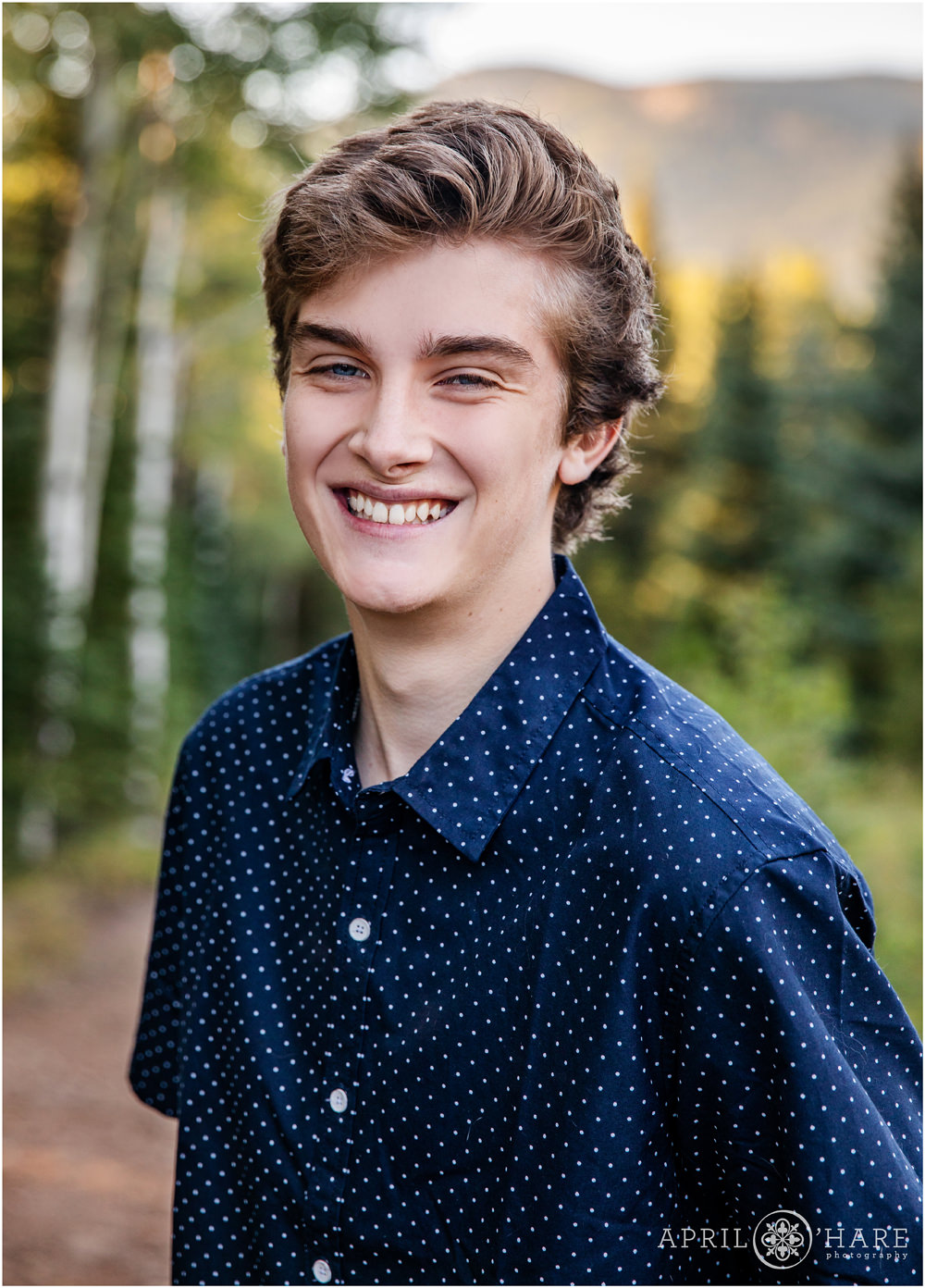 High School boy portrait in Evergreen Colorado wearing a short sleeved dark blue polka dot shirt