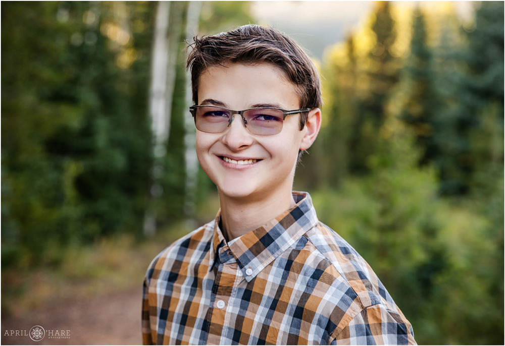 High school senior guy with transition lens glasses in the woods of Evergreen Colorado