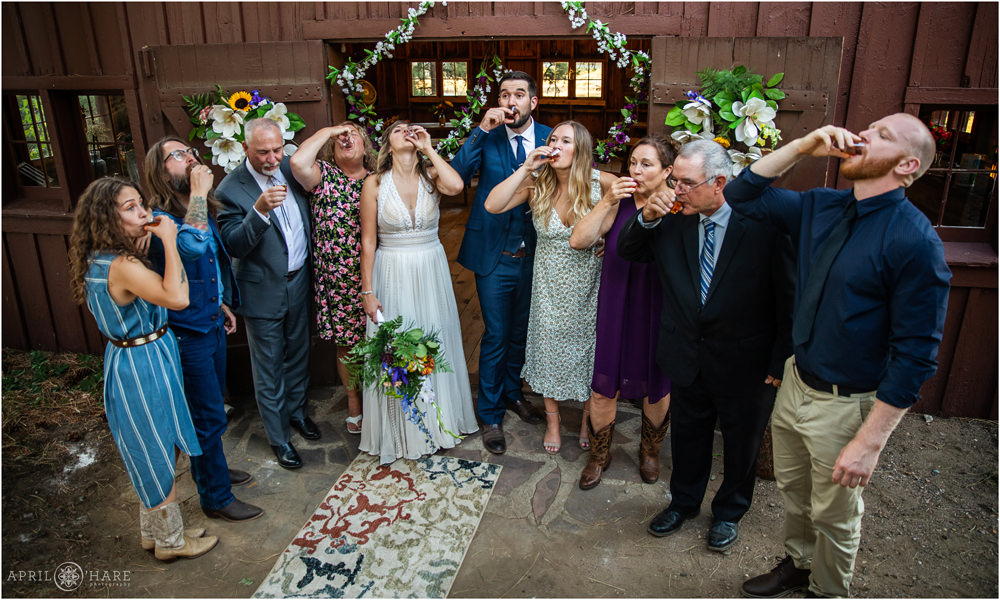 Entire wedding does a shot together outside of the rustic barn on Lookout Mountain in Golden Colorado