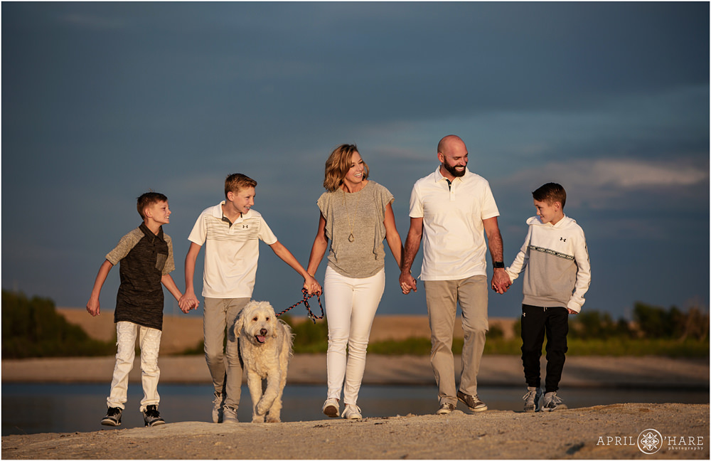 A beautiful family photo walking along the beach together with their white dog at Aurora Reservoir