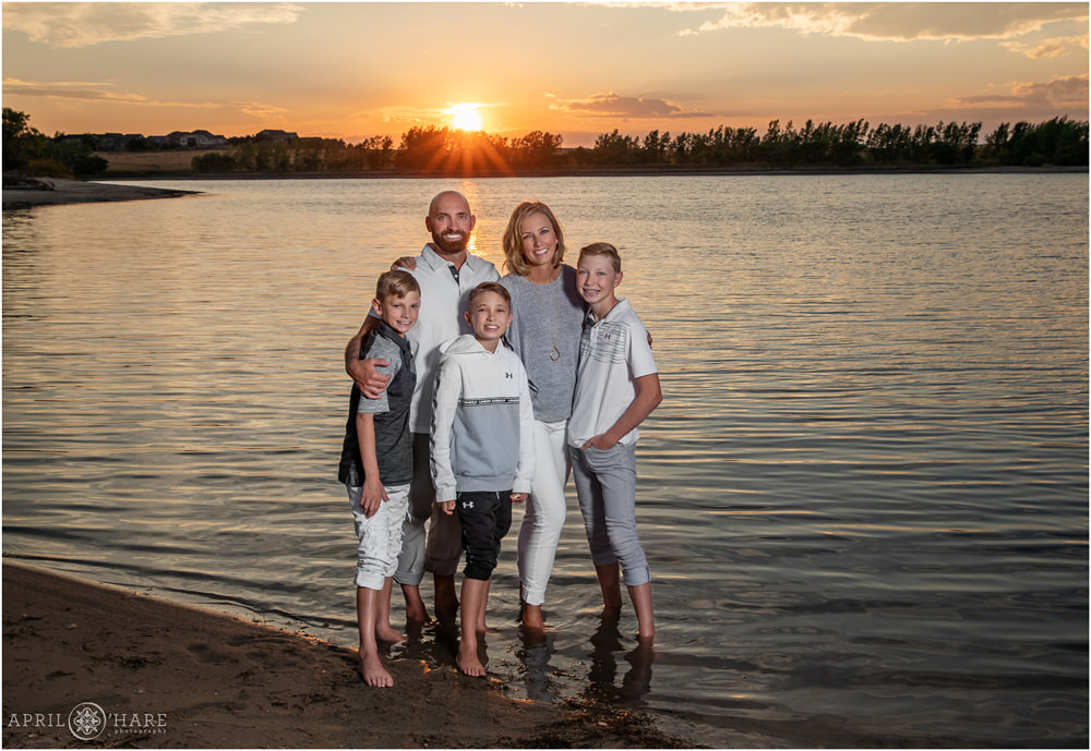 Gorgeous sunset photo for a family of 5 wearing gray and white as they stand in the water at Aurora Reservoir at their family portrait session