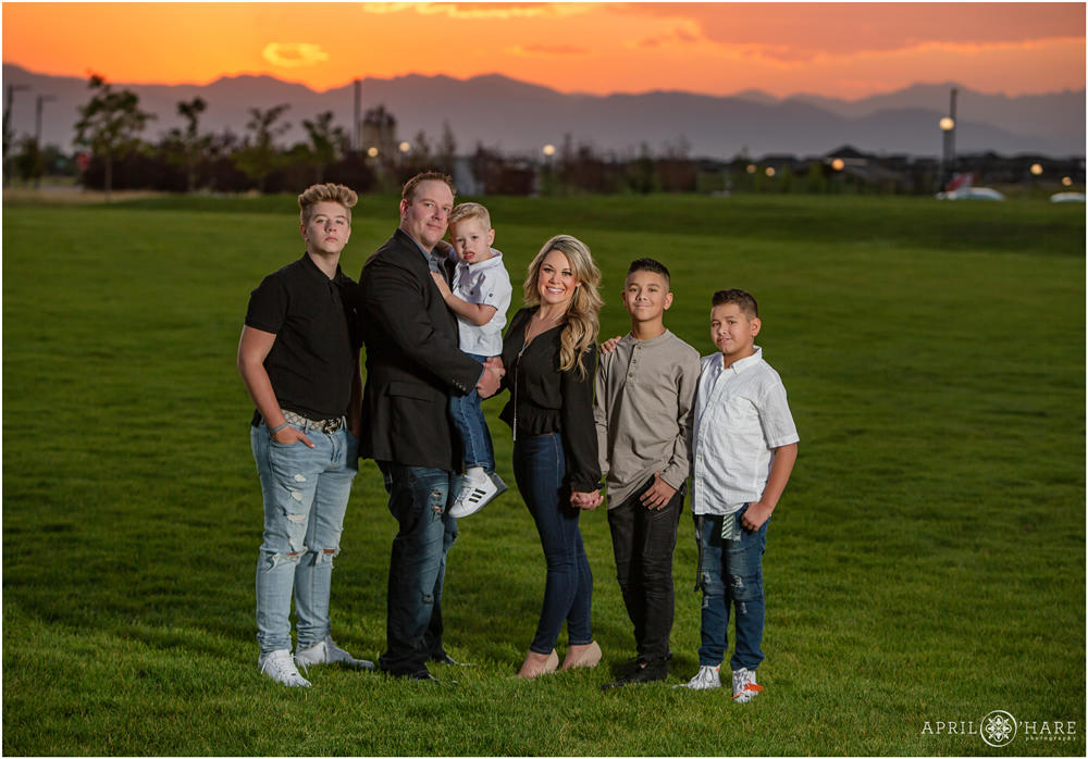 A blended family of 6 with 4 sons wearing black, white, and gray pose at Prairie Meadows Park in Northeast Denver Colorado