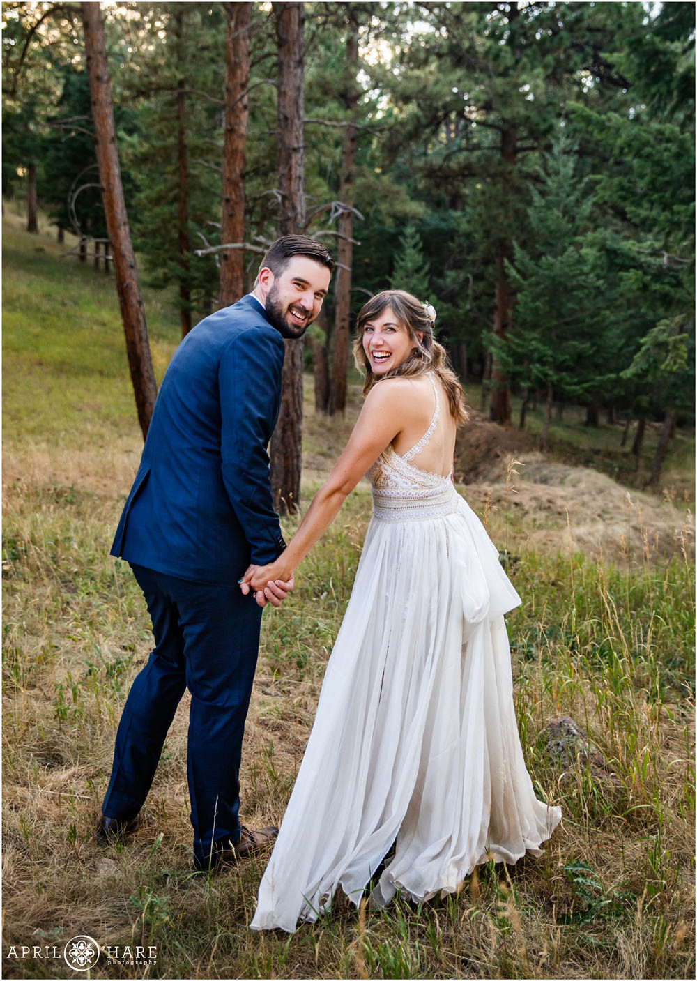 Bride and groom look over their shoulders and laugh on their wedding day in Colorado