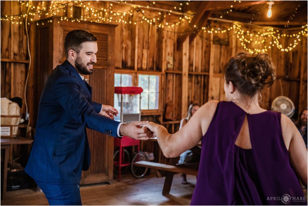 Groom dances with his mom on his wedding day inside a cute rustic barn on private property