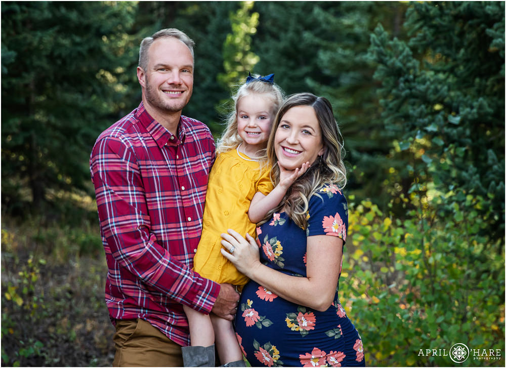 Adorable photo of a family of 3 with mom expecting another daughter at a woodsy location in Colorado