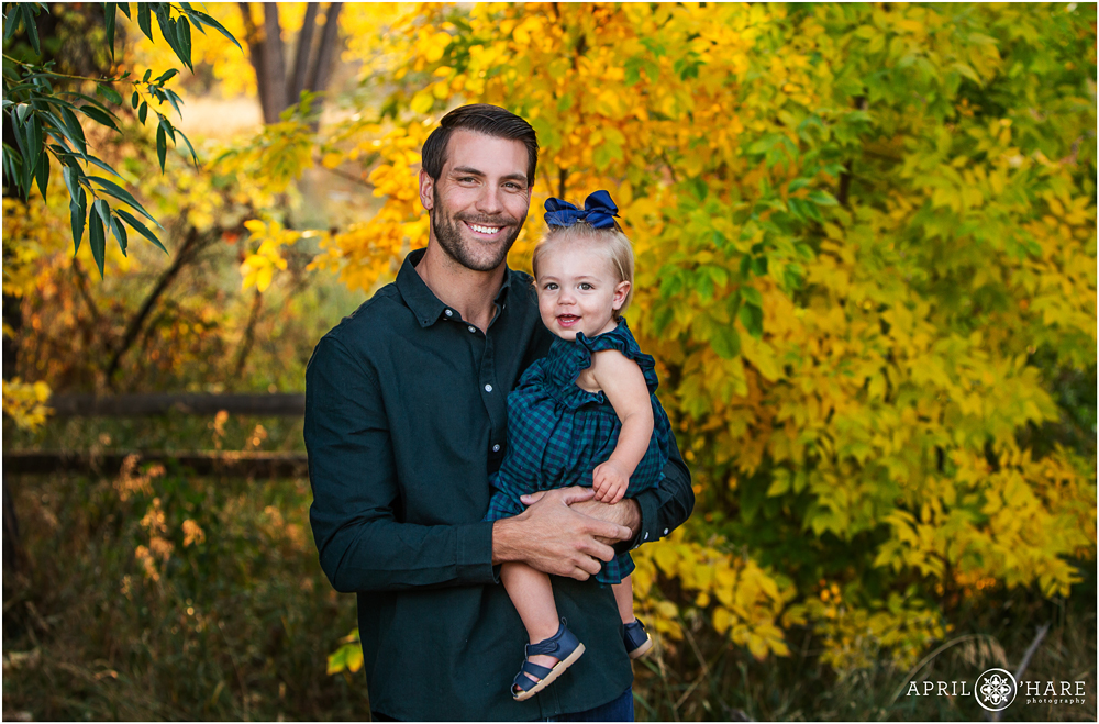 A father holds his one year old daughter with a beautiful fall color backdrop at the Mary Carter Greenway Trail