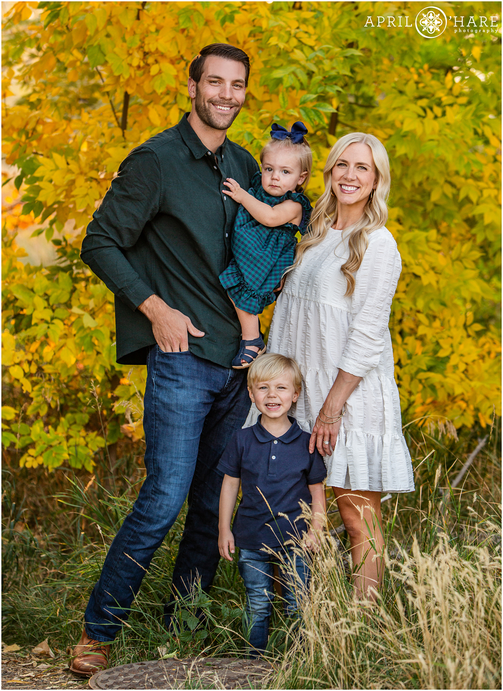 A family of four pose with fall color backdrop at the Mary Carter Greenway Trail in Littleton