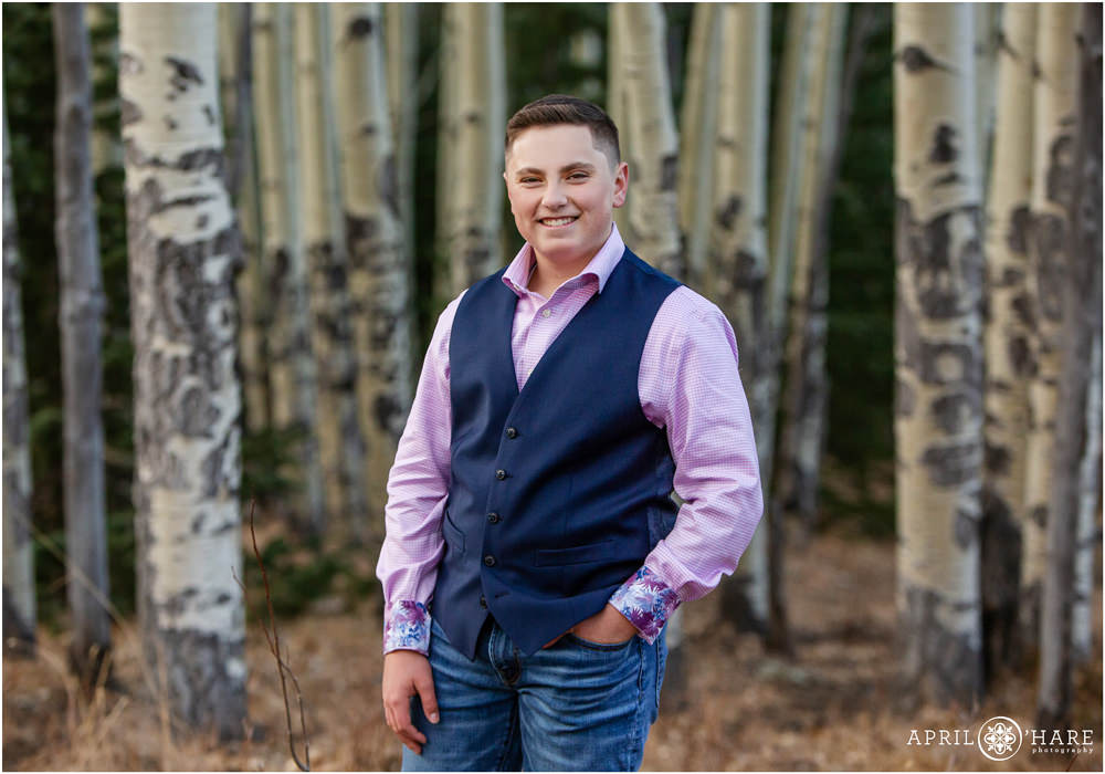 Cute portrait of a young teenager wearing a navy blue vest and light pink button down shirt in an Aspen Tree forest in Colorado