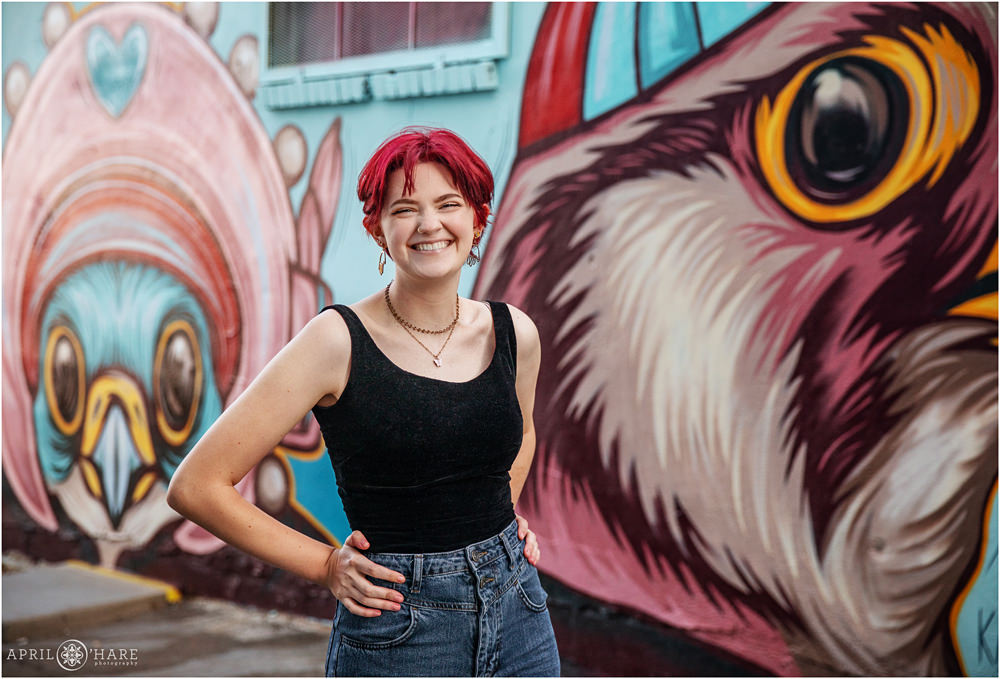 High school senior girl portrait in front of cartoonish animal head mural art by Kaitlin Zeismer in Five Points Neighborhood of Denver