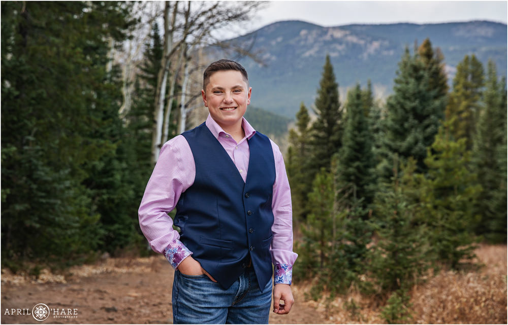 Nice portrait of a young teen boy wearing a nice pink button up shirt and a navy blue vest in the forest of Evergreen Colorado