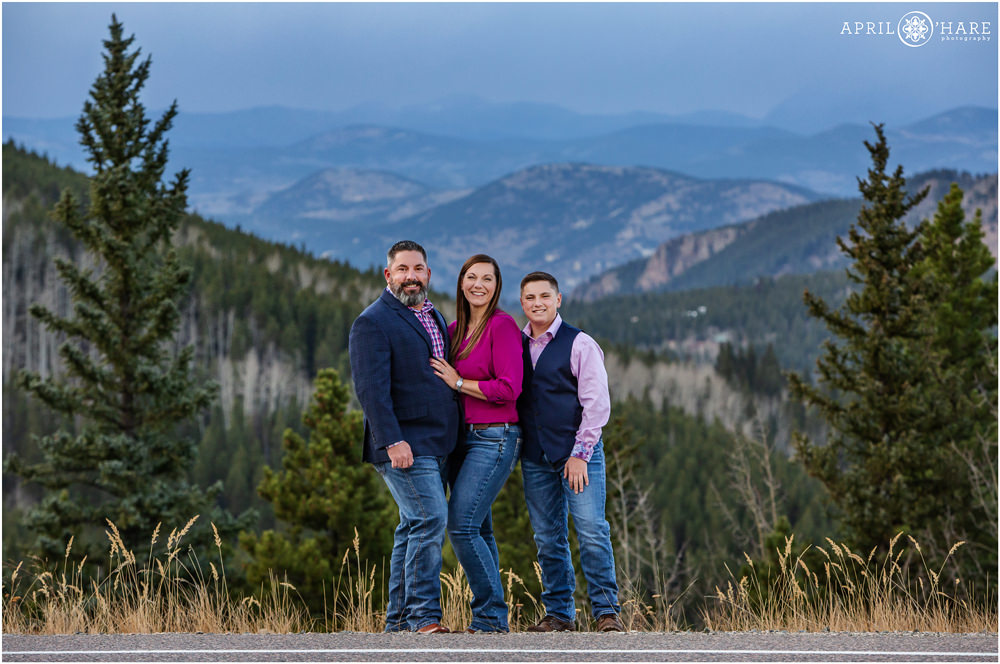Beautiful blue mountain backdrop for a family of three in Evergreen Colorado wearing navy blue and pink clothing