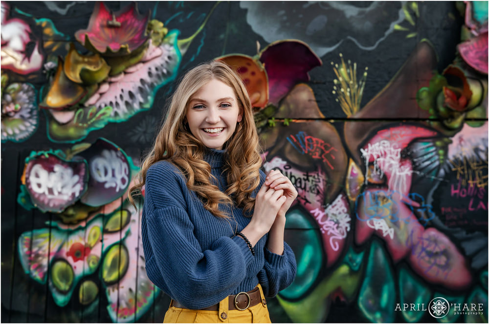 Fun and happy senior portrait in front of a 3D art wall in an alley in North Denver