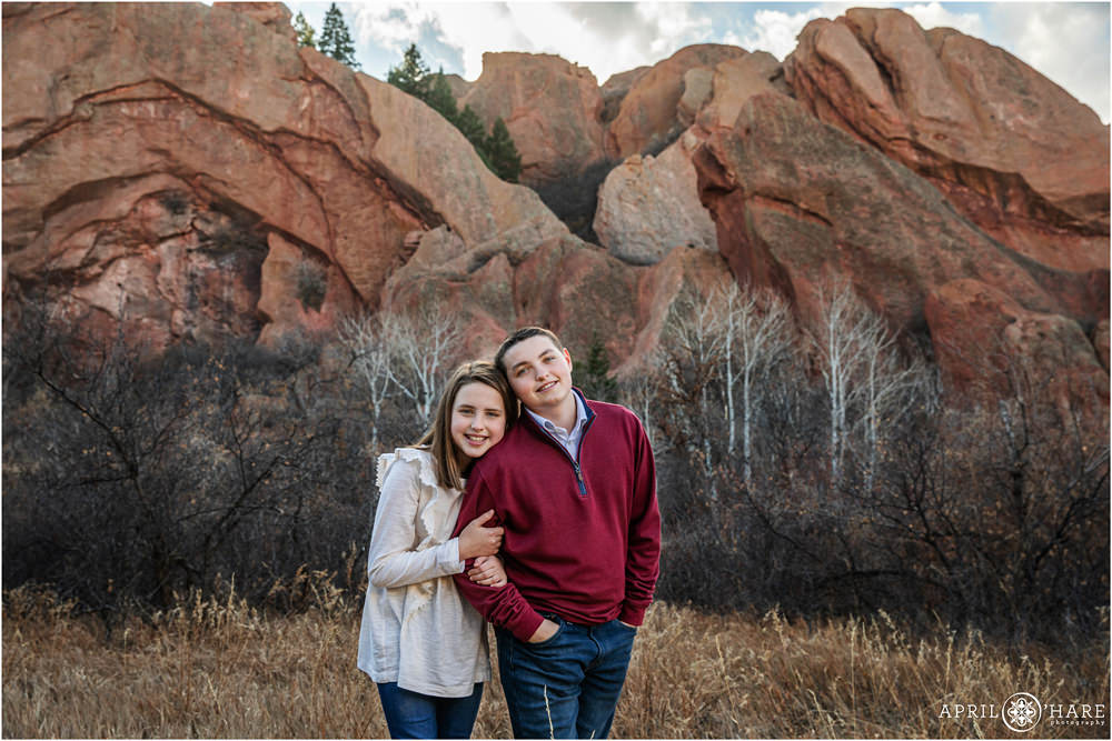 Siblings pose for a picture together with the dramatic red rock scenery in the backdrop at Roxborough State Park in Colorado