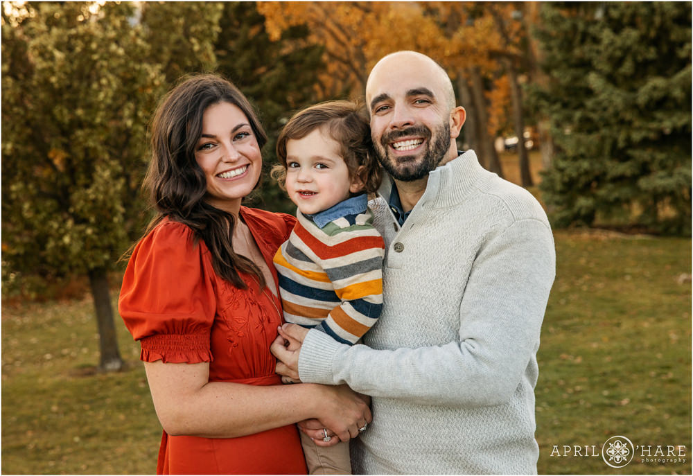 Aorable family photo with a young toddler boy wearing fall colors at Viele Lake in Boulder