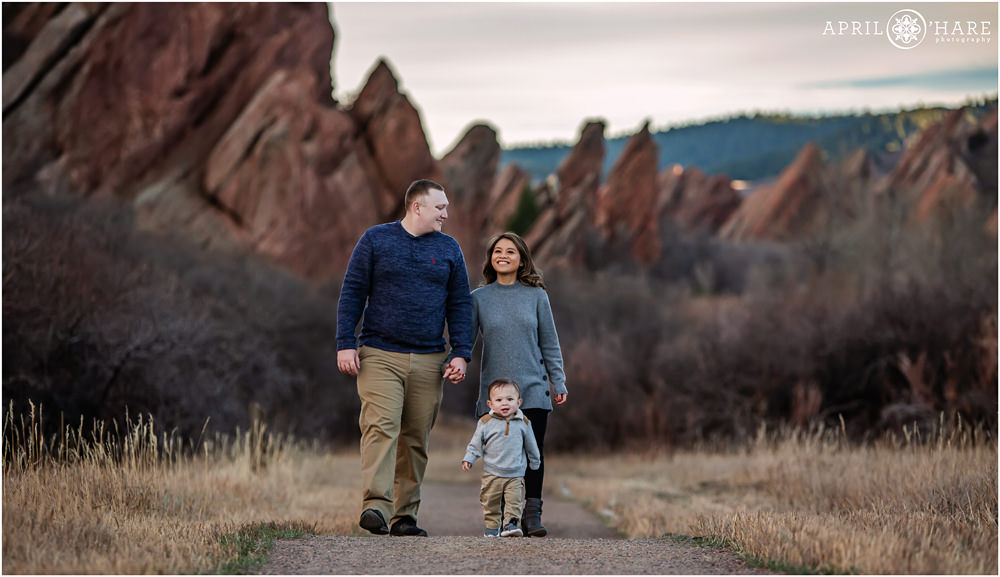 Cute Family of 3 with a young son walk together on the path at Roxborough State Park during winter in Colorado