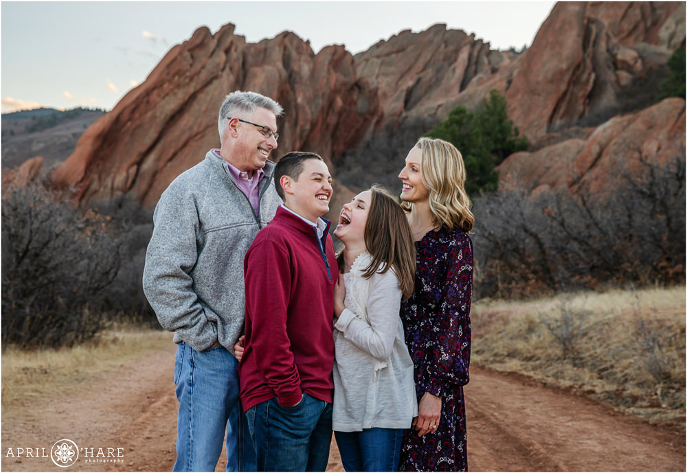 A cute candid photo for a family of four with beautiful red rock formations at Roxborough State Park in Colorado