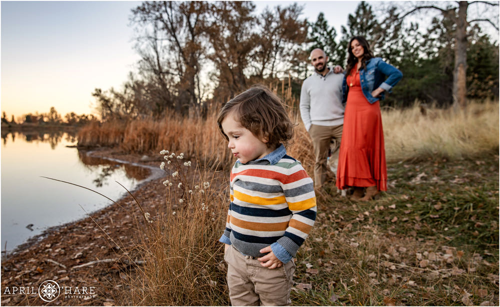Mom and dad look on at their son as he explores Viele Lake during fall in Boulder CO