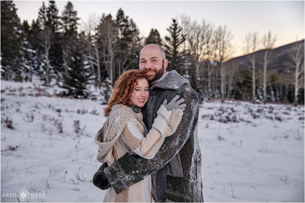 Mom and dad get their own couples photo in a beautiful mountain meadow covered in snow during winter