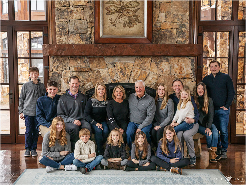 An extended family with 16 people pose in front of a huge stone fireplace at their vacation home in Beaver Creek Colorado