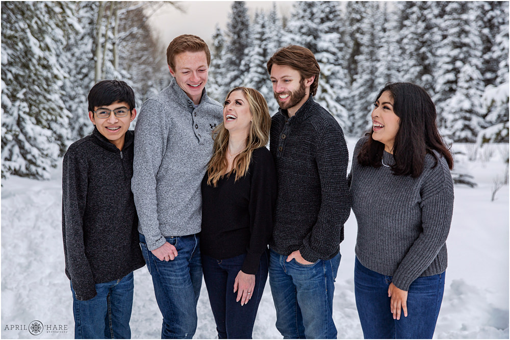 Siblings laugh together in a snowy wooded forest in Evergreen CO