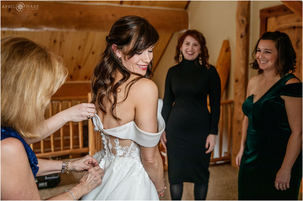 Bride gets help with her romantic off the shoulder wedding gown in Keystone Colorado