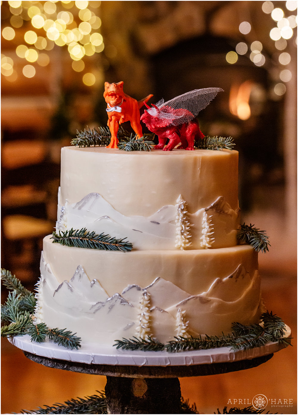 Dinosaur topped white wedding cake with mountains on it at Keystone Colorado wedding