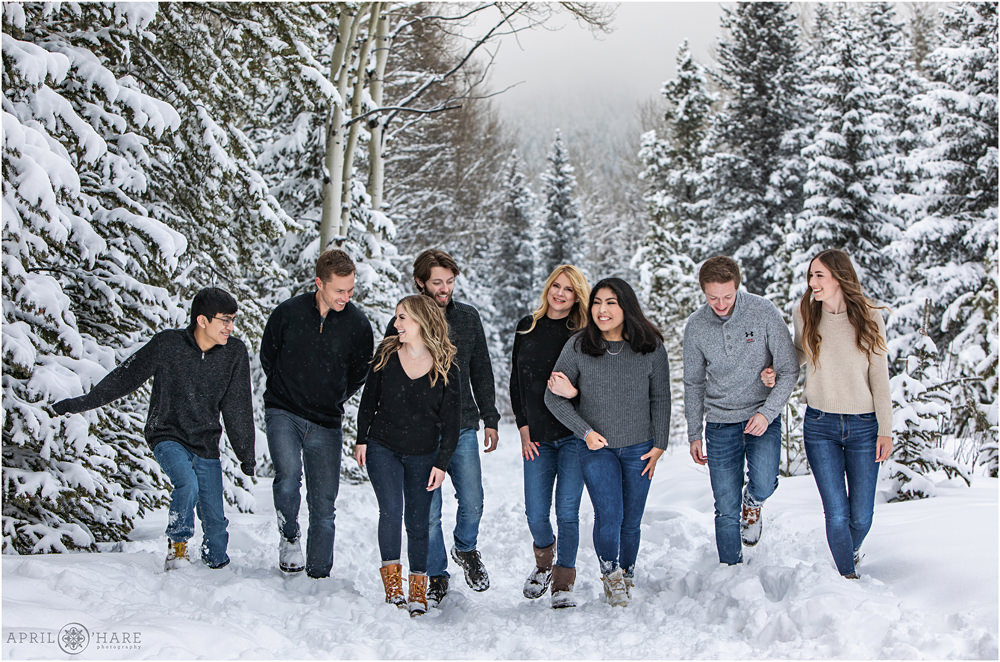 A family of 8 walk in a snowy forest setting for their Colorado family portrait session in Evergreen