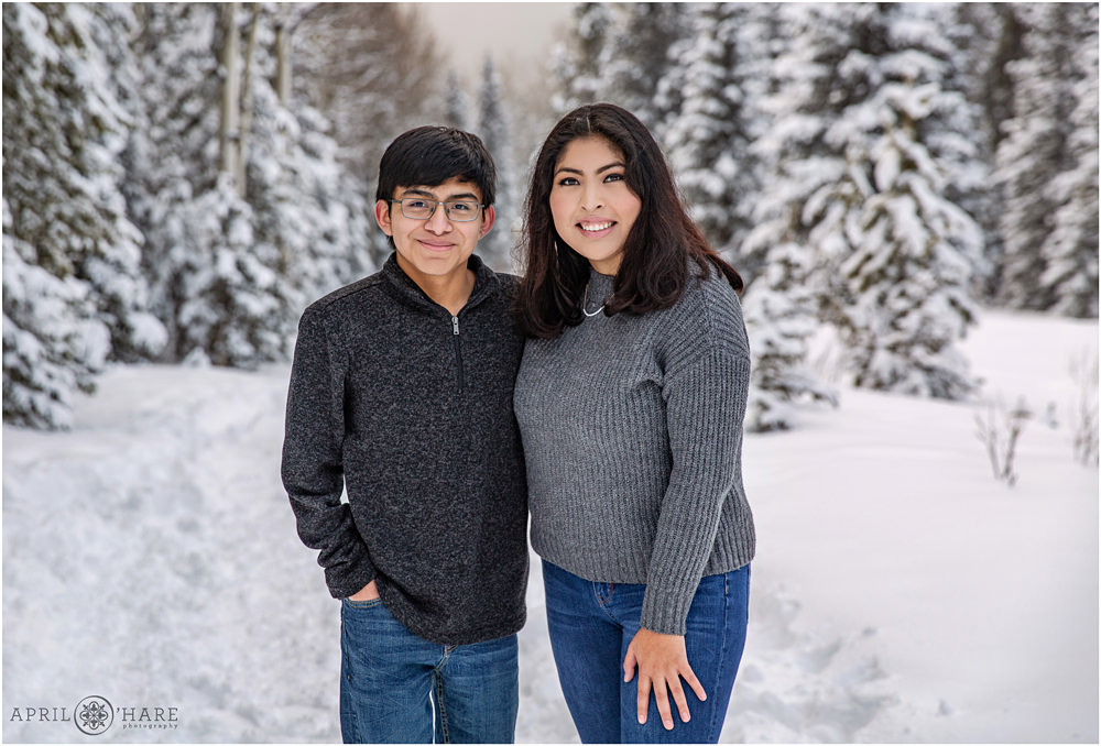 A brother and sister wearing shades of gray pose in a snowy winter wonderland in Colorado