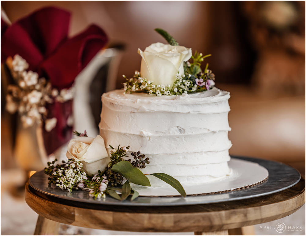 Detail photo of a single layer white wedding cake with green and white florals at Romantic RiverSong Inn Elopement