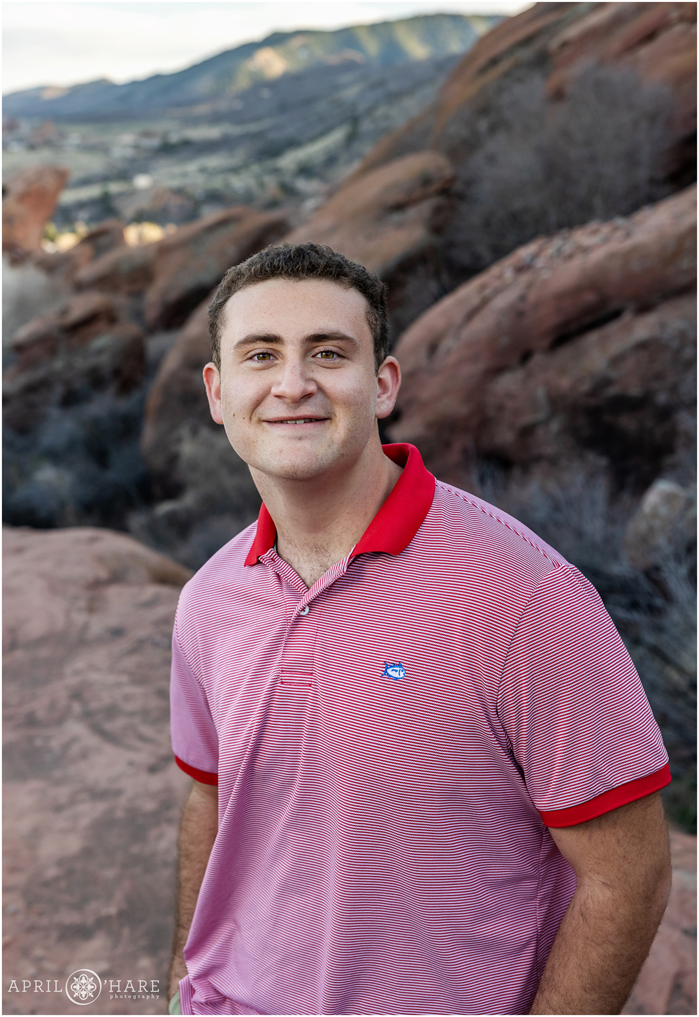 Senior photo of a teen boy wearing a red collared striped shirt at Red Rocks in Morrison Colorado