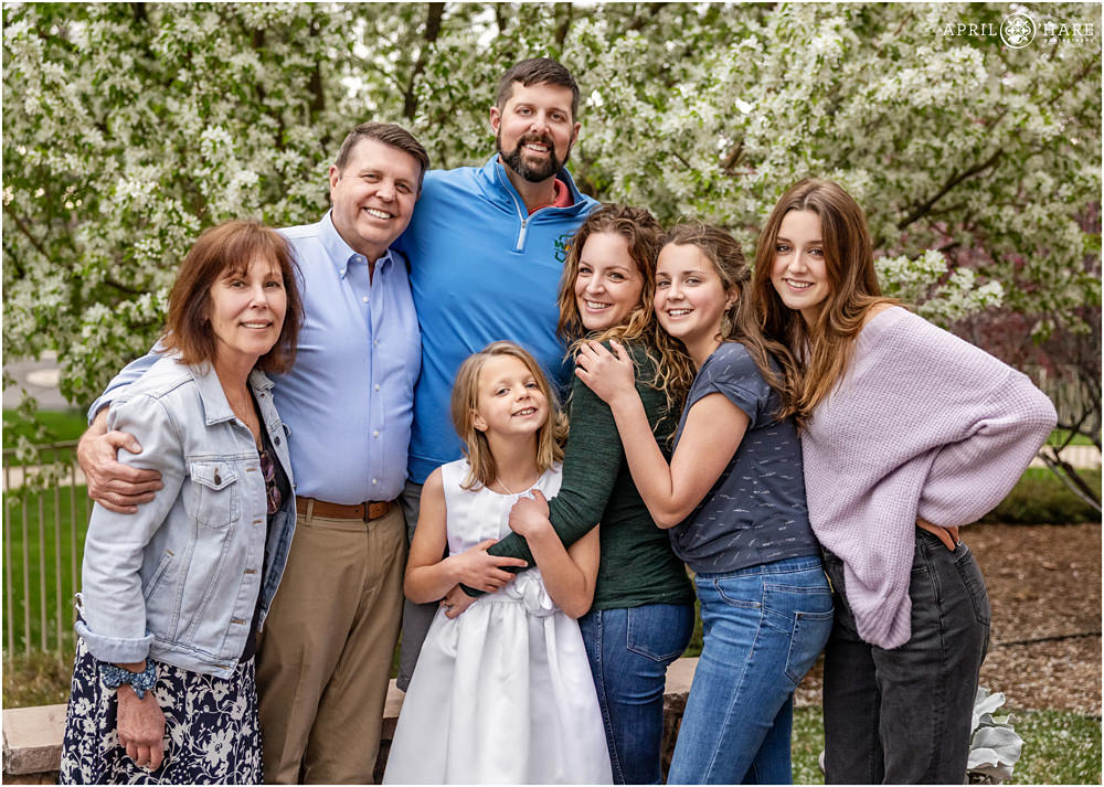 Denver First Communion photos for a family celebrating at home in their backyard with a spring blossom backdrop
