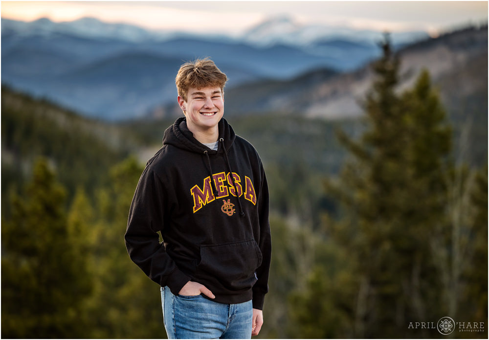 High school senior boy wearing a Black Colorado Mesa University with a mountain backdrop