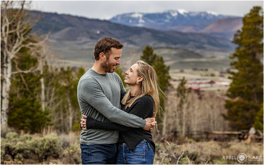 Couple smile at each other with a pretty mountain backdrop at Granby Ranch in Colorado