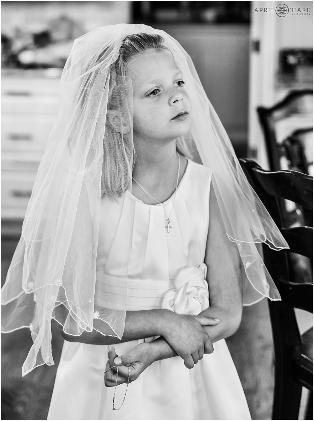 B&W candid photo of a girl on the day of her First Communion at home in Denver