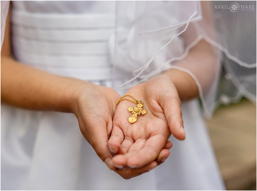 A little girl holds her gold cross necklace she got as a gift for her first communion in Denver Colorado