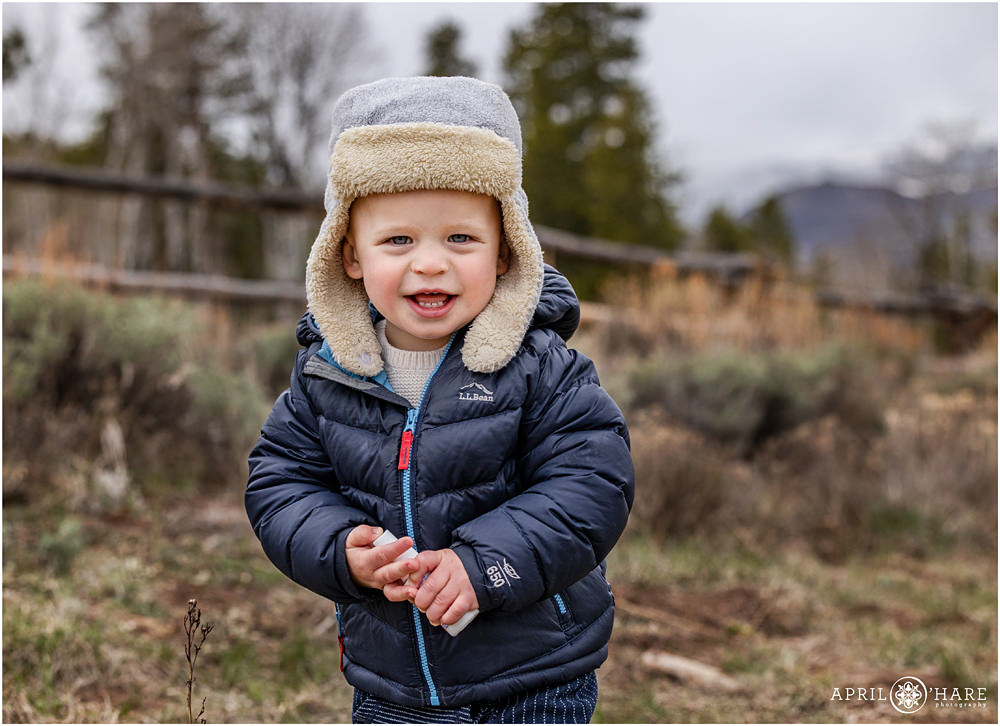 Cute little boy wearing a warm trapper style hat at this family photography session at Granby Ranch in Colorado