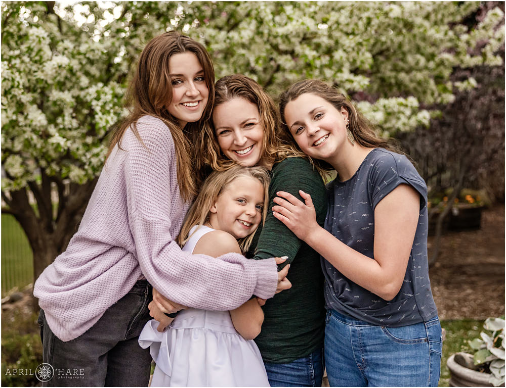Family photo of a mom with her 3 daughters for a First Communion in Denver Colorado with spring blossom backdrop