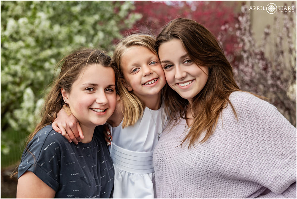 Three sisters pose for pretty spring photos for their little sister's first communion at their home in Denver